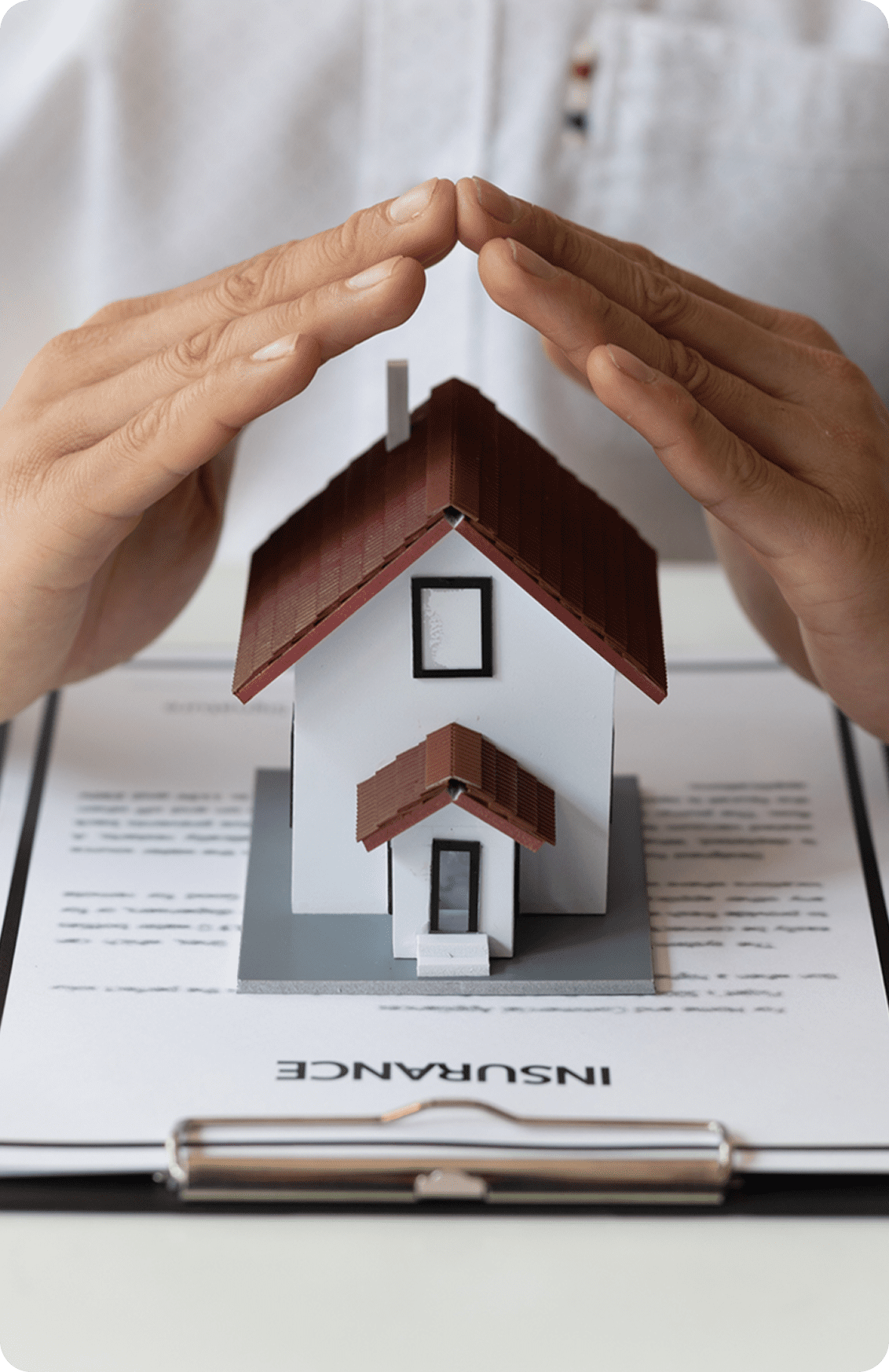 Hands protecting house model on insurance document