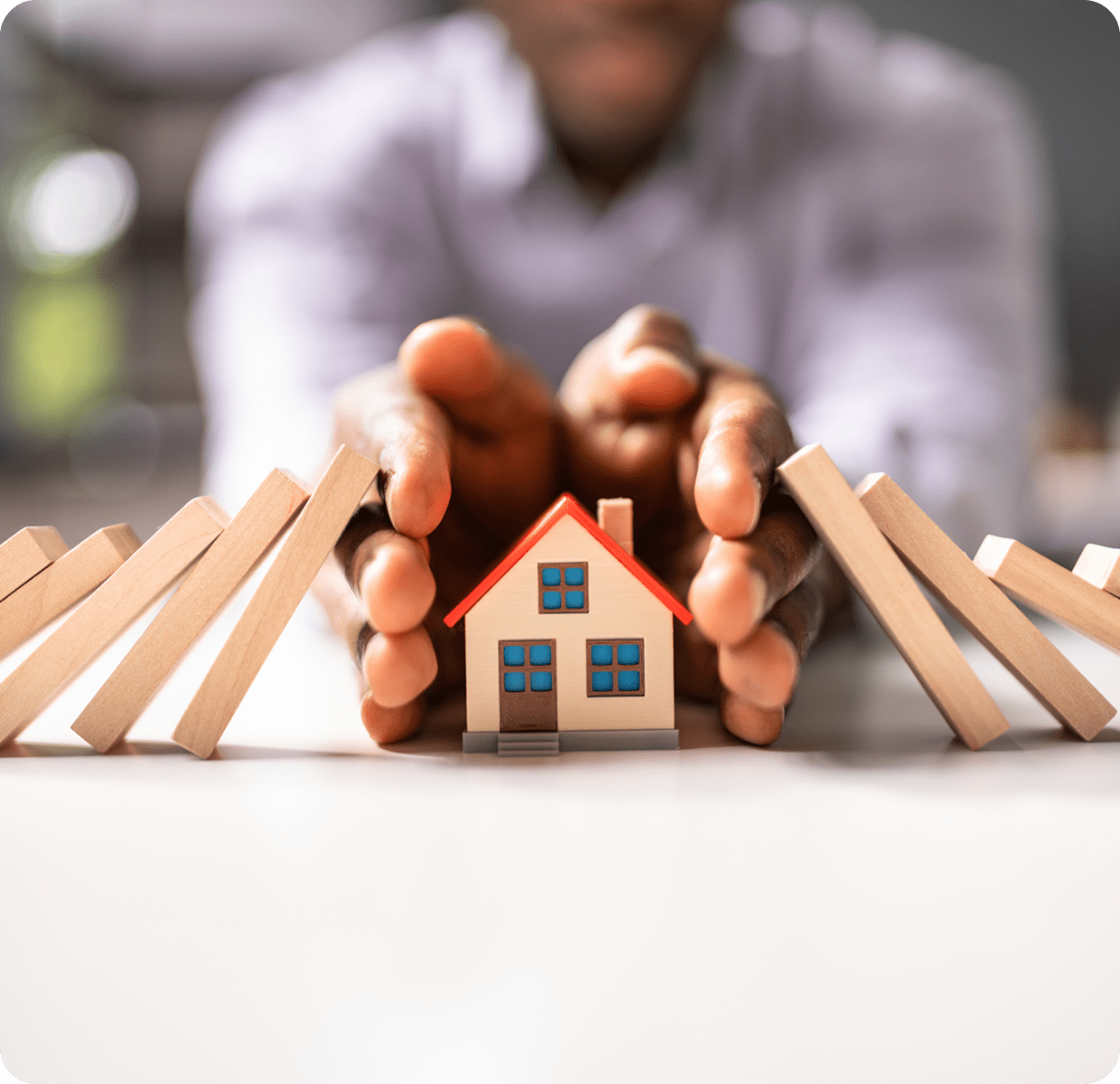 Hands protecting house from falling blocks