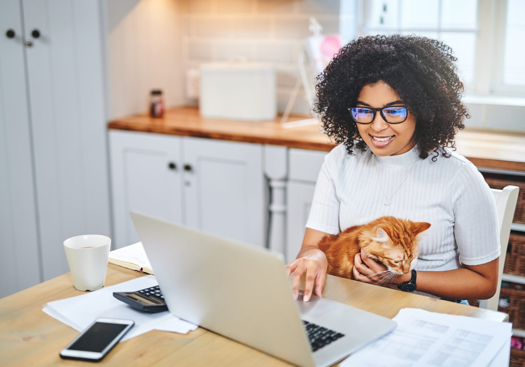 Woman working on laptop with cat