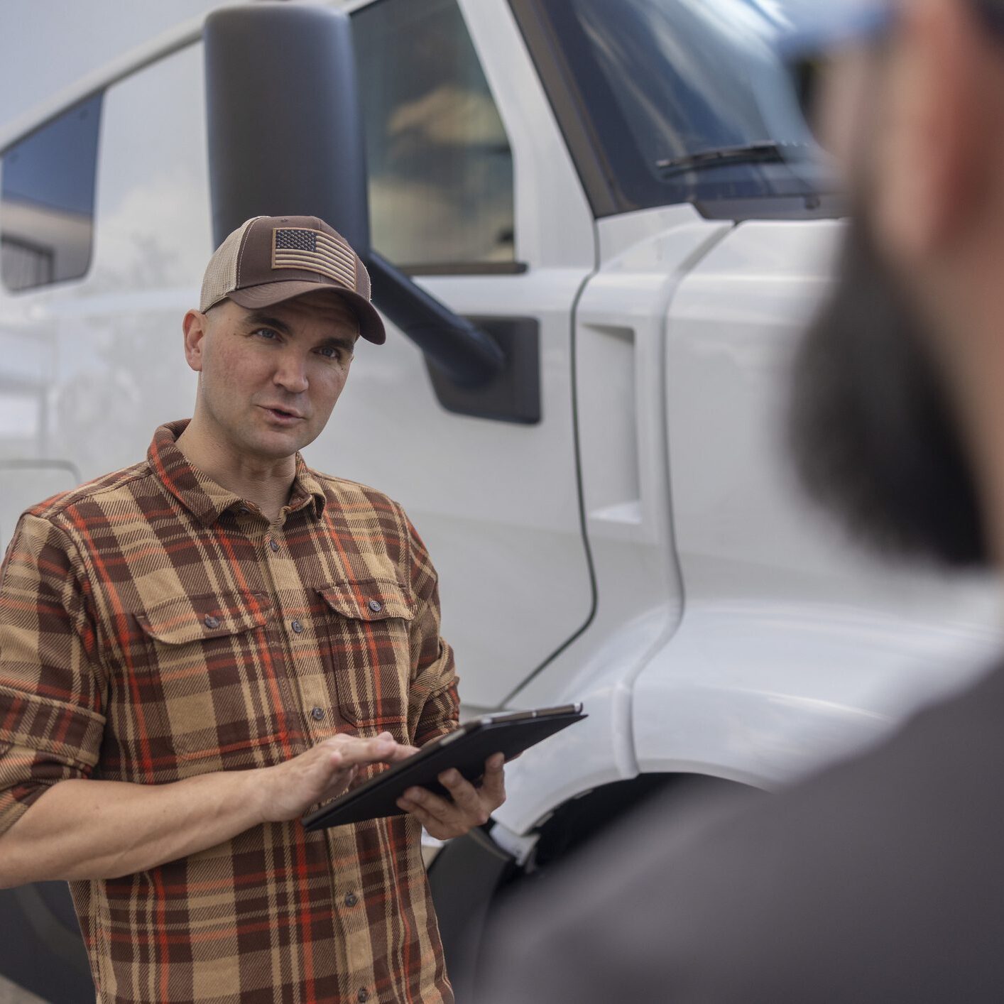 Driver holding tablet beside truck
