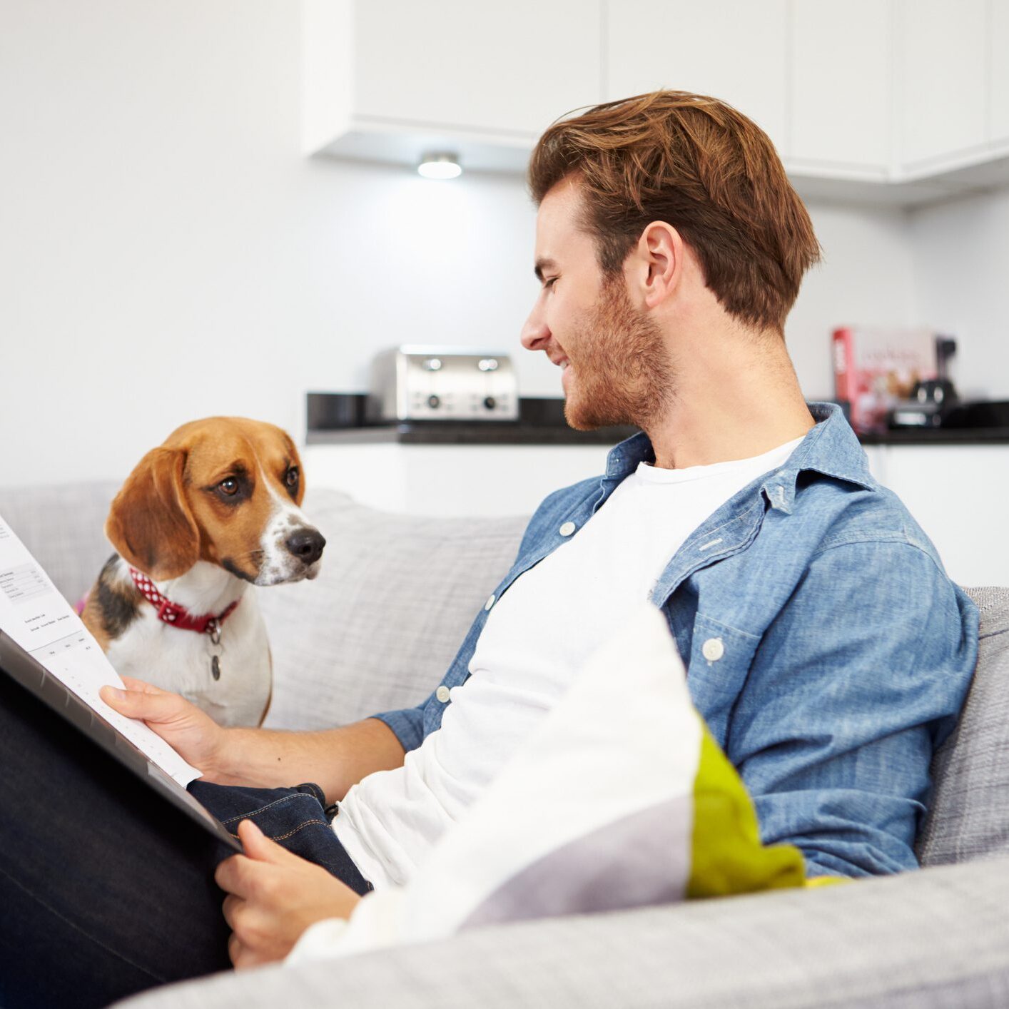 Man reading on couch with dog
